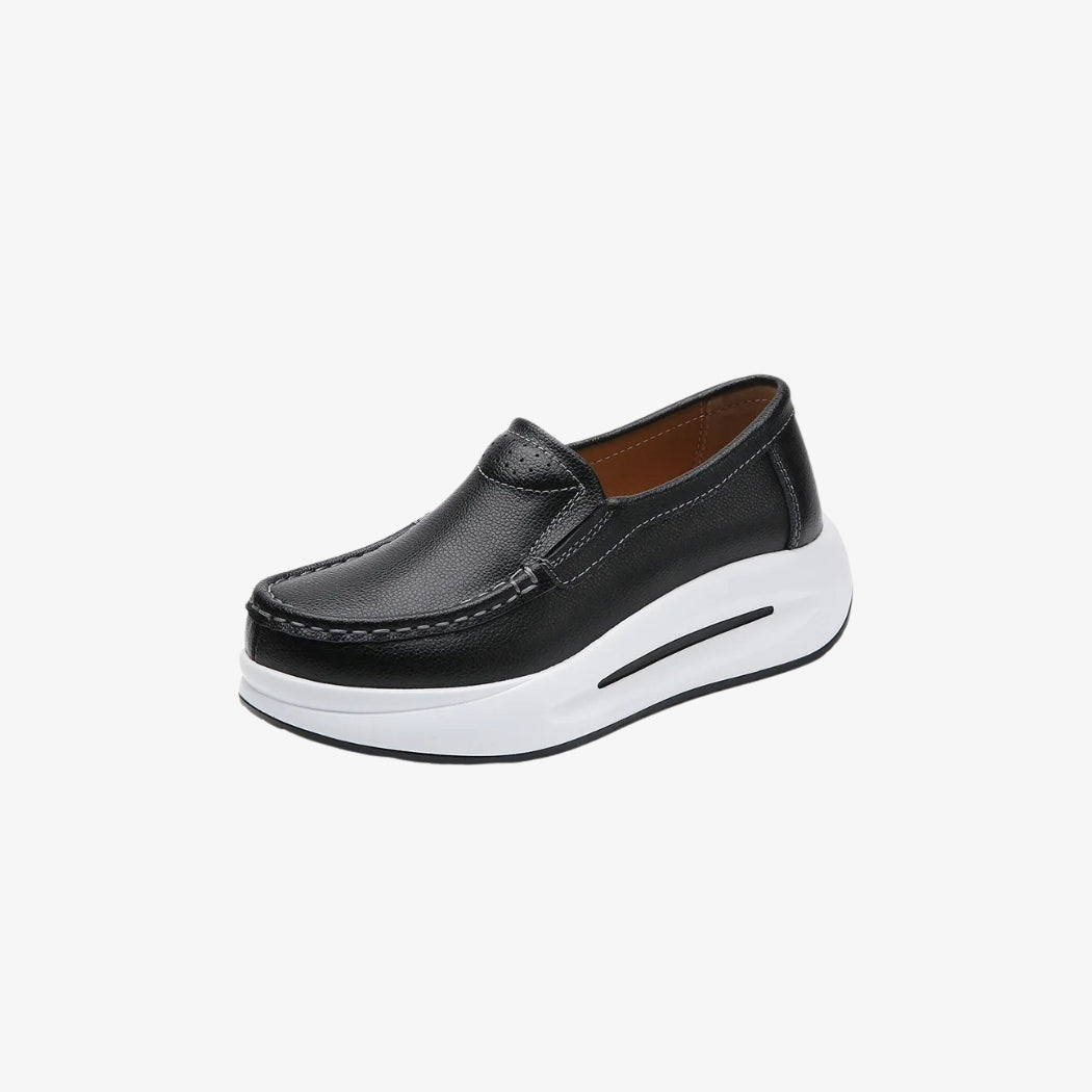 Mocassini da donna in pelle nera con suola spessa bianca per uno stile moderno e comodo. Il design minimalista include cuciture a vista e una calzata facile, perfetti per un look elegante e al tempo stesso casual.