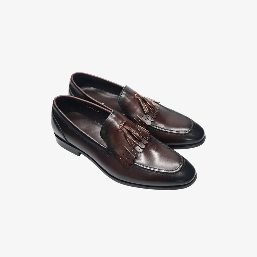 Mocassini da uomo in pelle lucida marrone con una finitura elegante. Queste scarpe sono ornate da nappe decorative e frange traforate sul collo del piede, per uno stile sofisticato e senza tempo, perfetto per le occasioni formali o professionali.