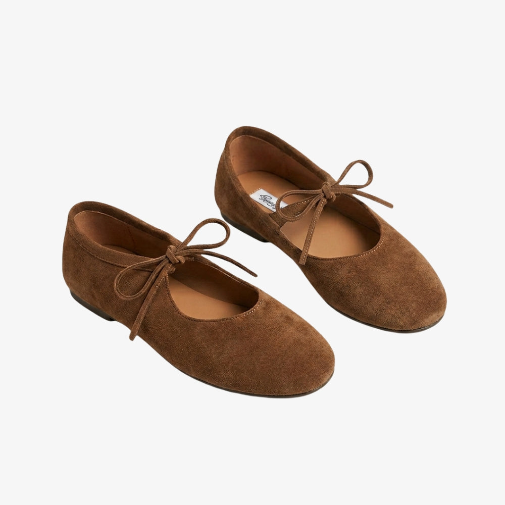 Ballerina mocassino in pelle scamosciata marrone cognac, con un nodo sul davanti, su sfondo grigio