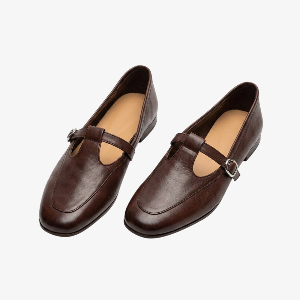 Mocassino ballerina stile vintage con cinturino a T, di colore marrone, su sfondo grigio