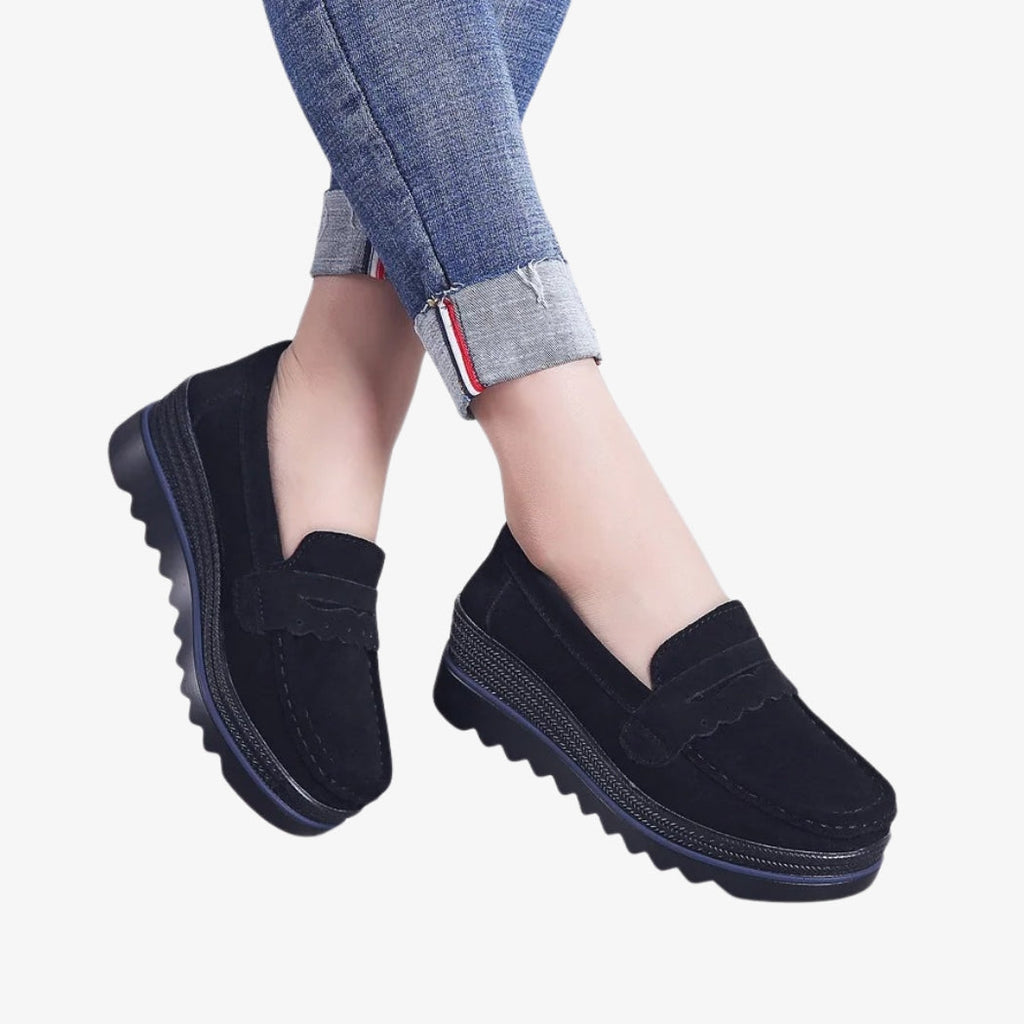 Mocassini da donna in camoscio nero, eleganti e comodi, con suola con zeppa scolpita per una maggiore stabilità. Il design include dettagli decorativi sul davanti e una cucitura a vista, perfetti per uno stile moderno e disinvolto.