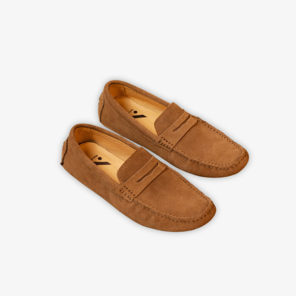 mocassino classico marrone appoggiato a terra su sfondo beige