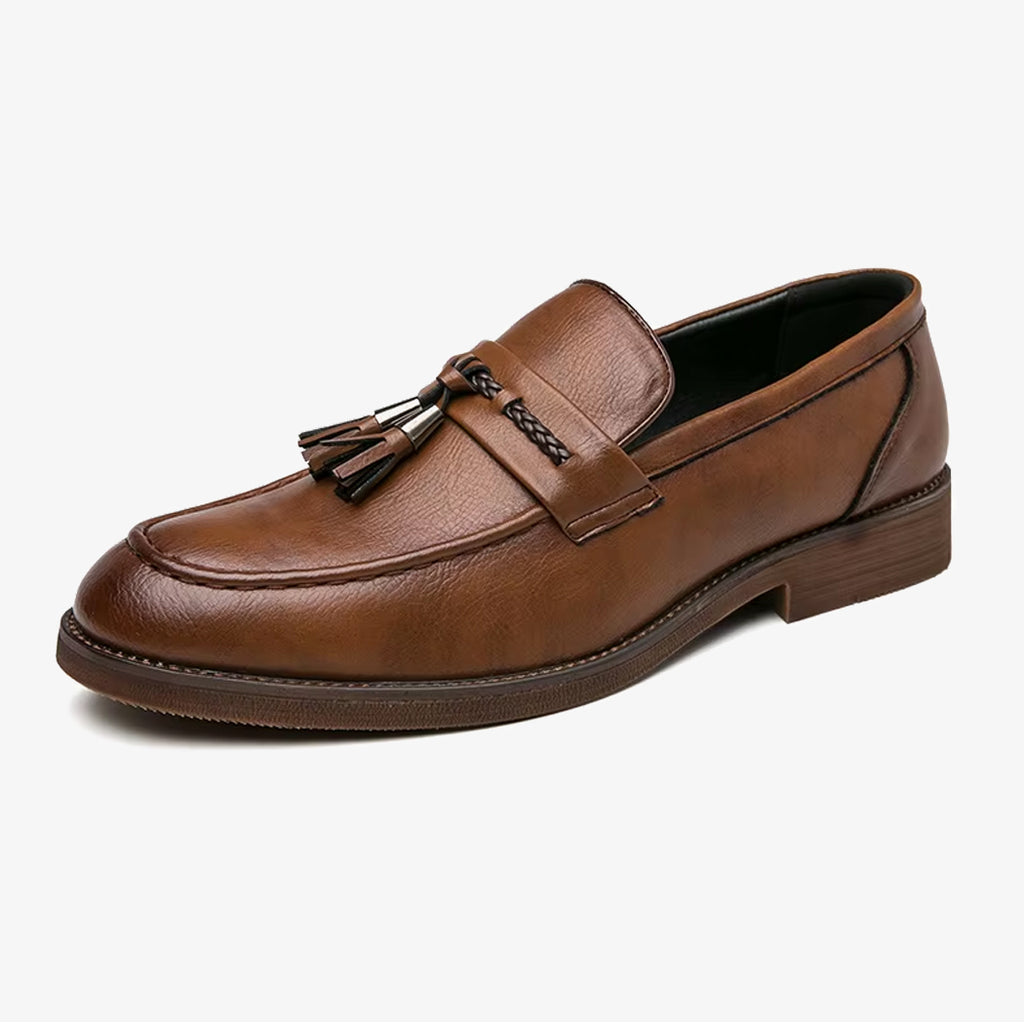 Un mocassino elegante da uomo in pelle marrone con nappina su sfondo bianco