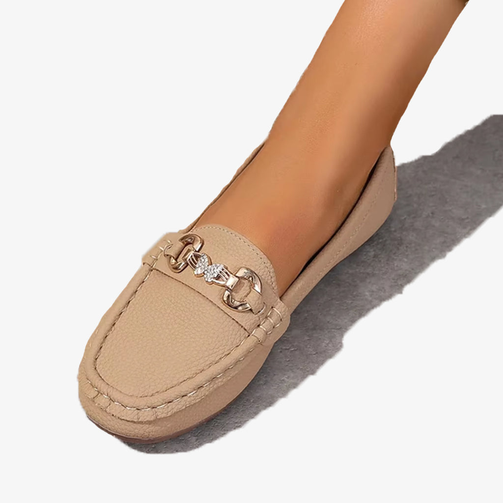 Mocassini beige in similpelle con catena e farfalla in strass su sfondo bianco