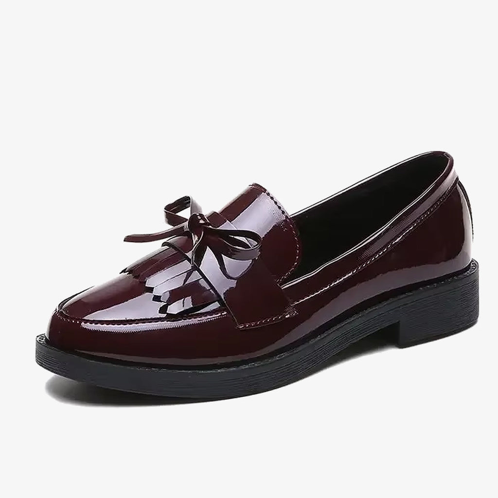 Mocassini in vernice bordeaux con frangia e fiocco su sfondo bianco