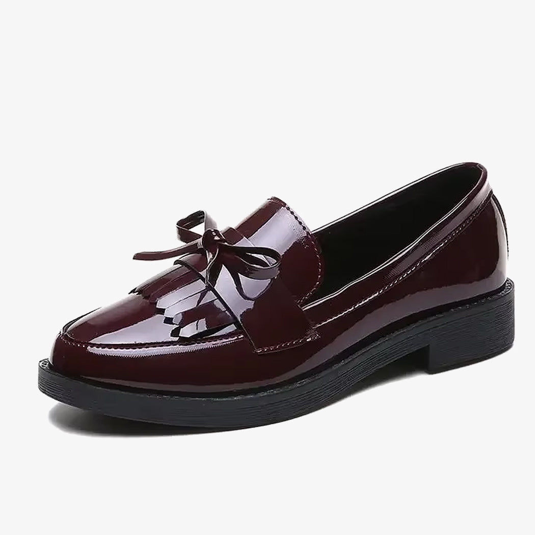 Mocassini in vernice bordeaux con frangia e fiocco su sfondo bianco
