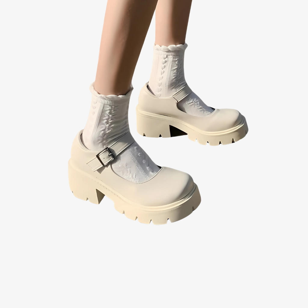 Donna di cui si vedono solo le gambe, che indossa mocassini beige con plateau e un cinturino sul collo del piede, con calzini bianchi.