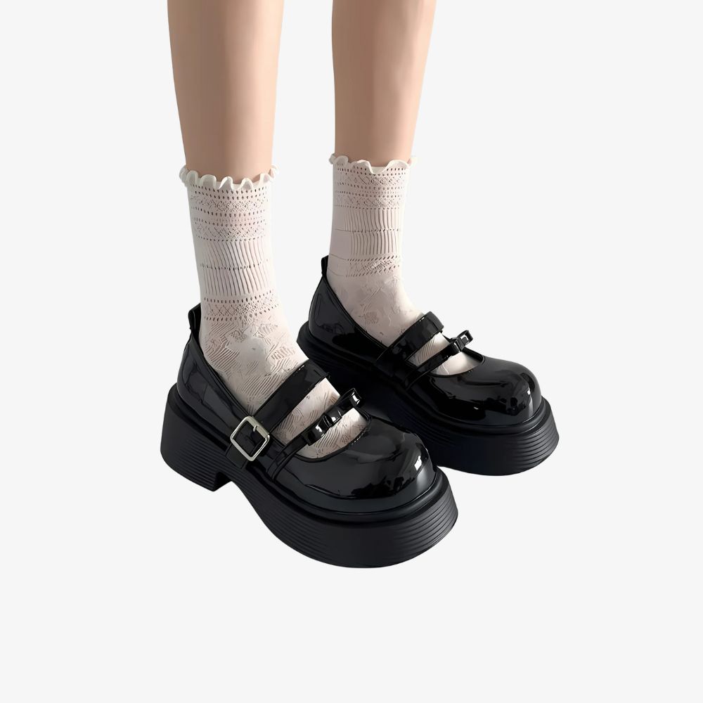 Gambe di donna con mocassini neri con plateau e due cinturini, con calzini alti bianchi.