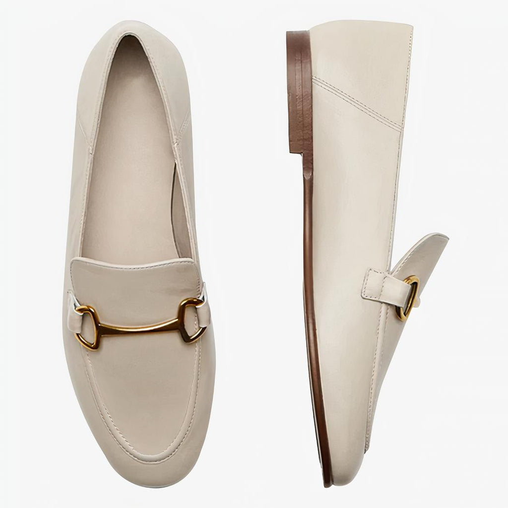 Su uno sfondo chiaro si vede un paio di mocassini beige sottili e leggeri in vera pelle