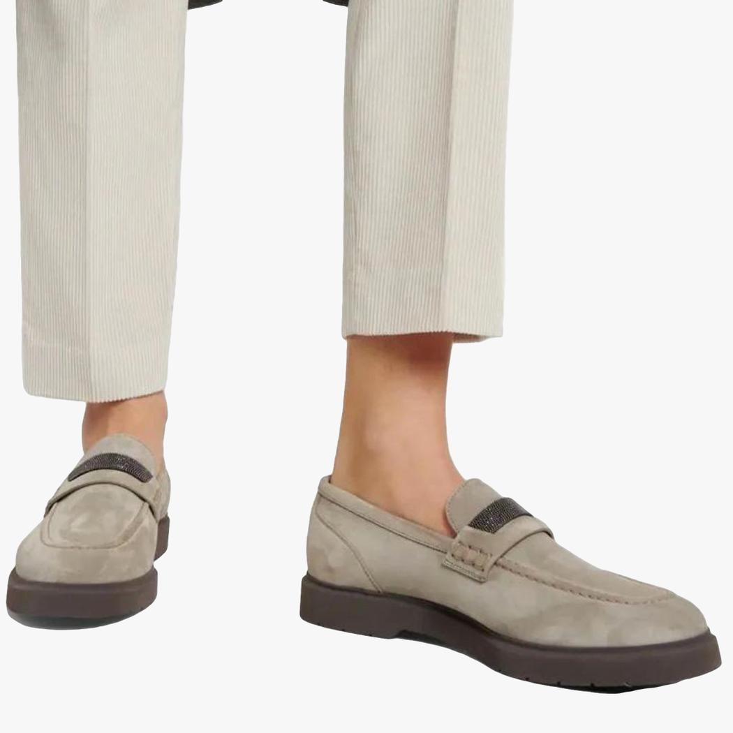 si vedono i piedi di una donna che indossa un pantalone da tailleur beige e mocassini grigi in vero camoscio da donna