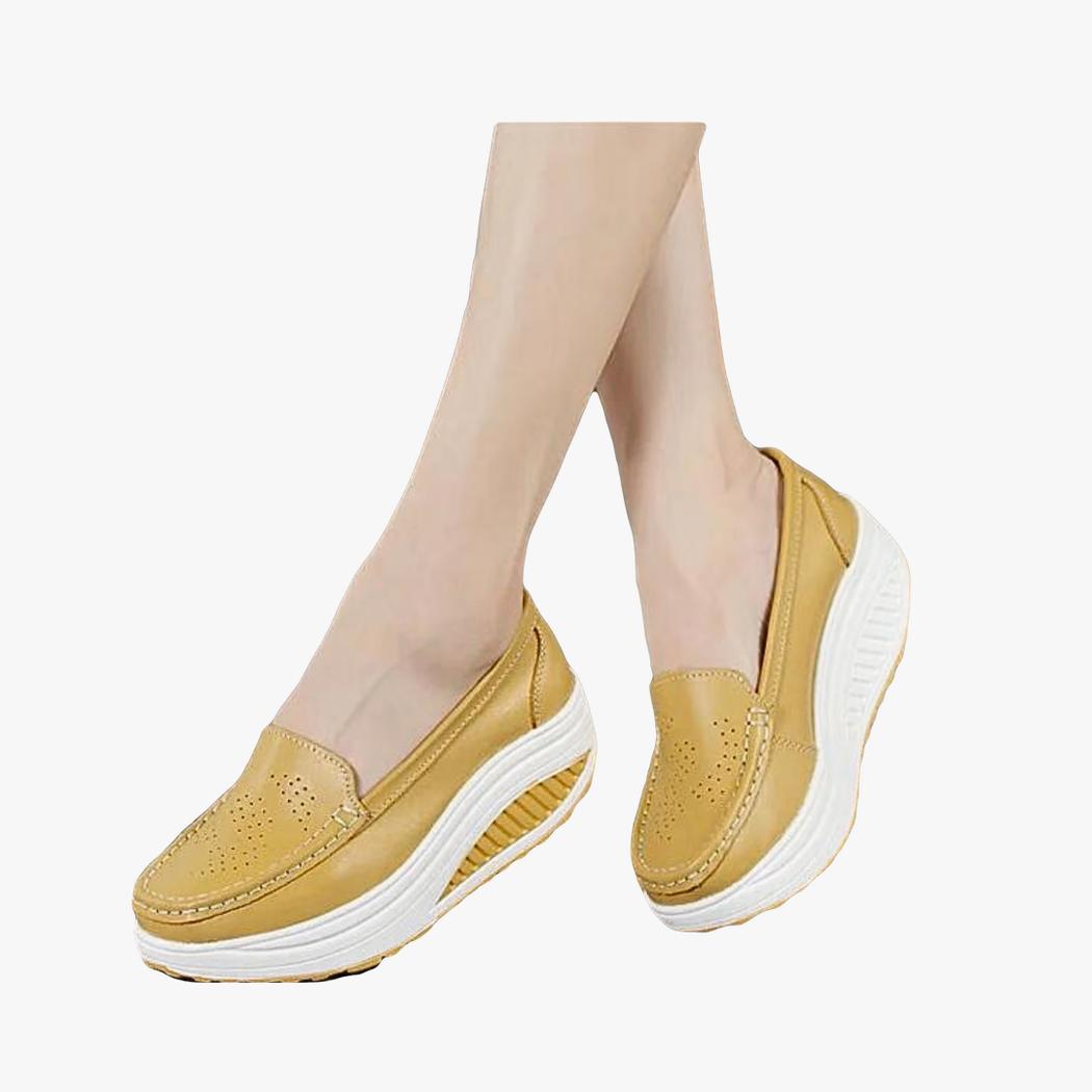 Si vede una donna, ma solo i suoi piedi, con mocassini traspiranti colorati con platform color cammello
