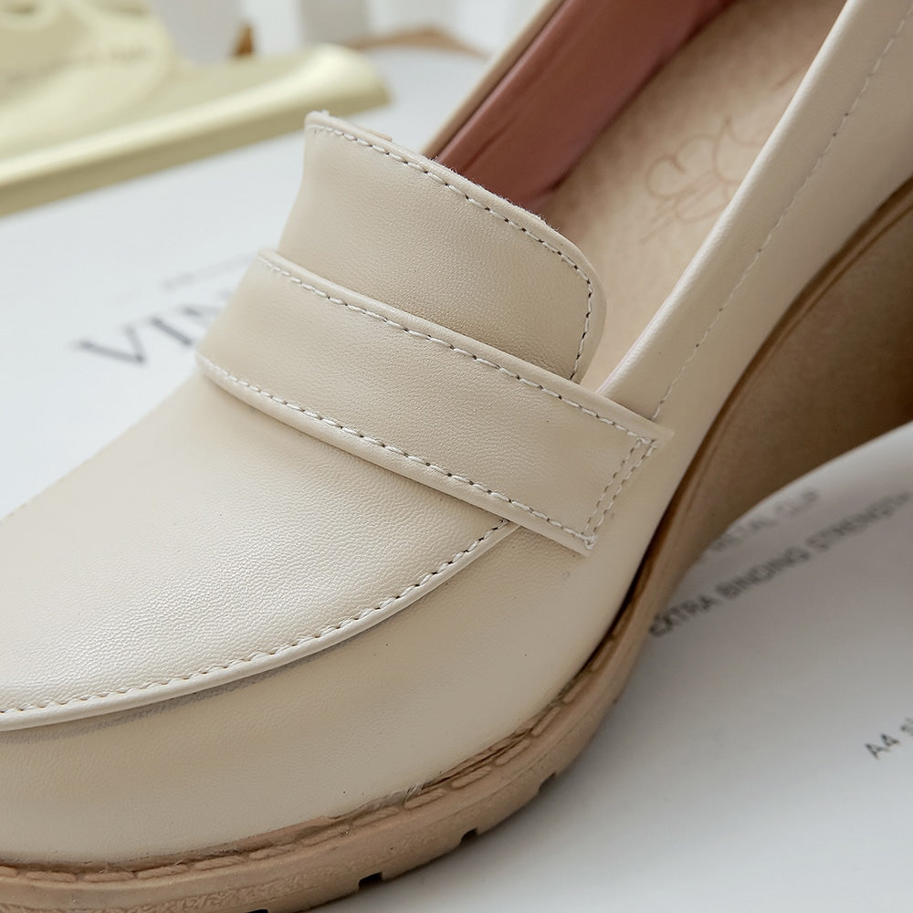 Foto di un mocassino con zeppa beige su un giornale bianco