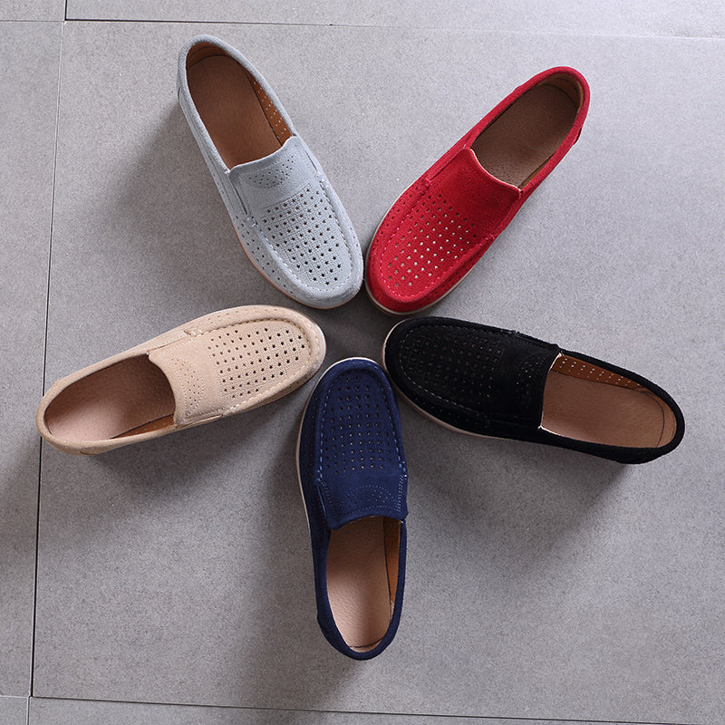 5 mocassini disposti a stella su un pavimento grigio, nei colori grigio, beige, blu, nero e rosso