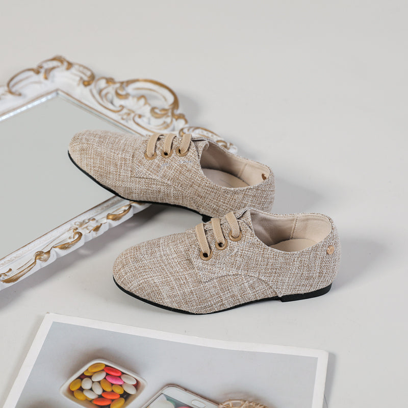 Mocassini slip-on da bambino in tessuto di colore neutro con sfondo beige, specchio e poster