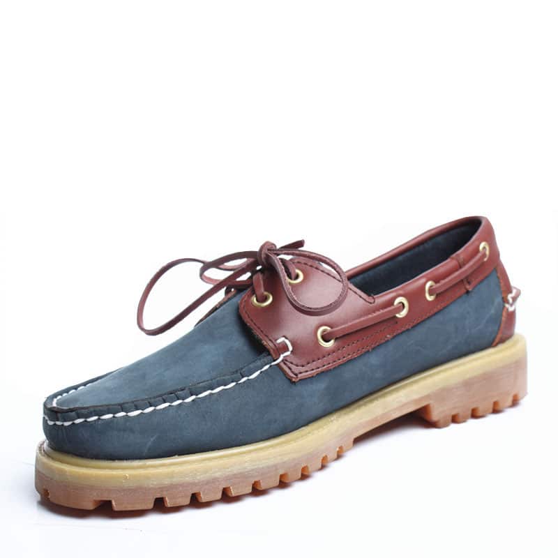 Mocassino da barca blu e marrone su sfondo bianco.