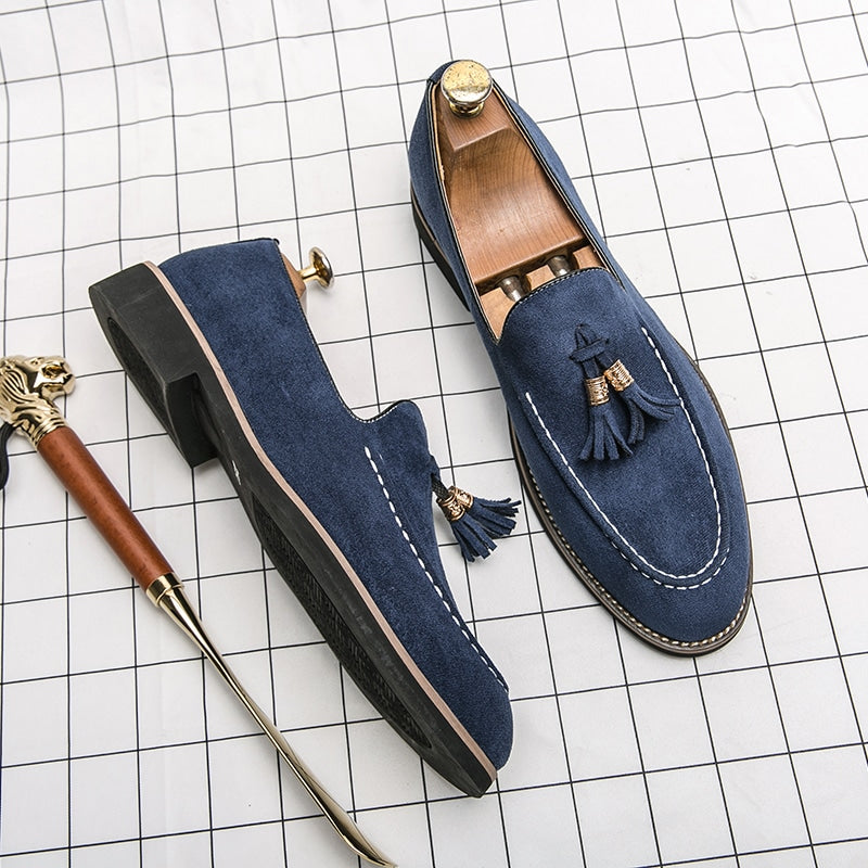Mocassini blu con una scarpa laterale, tutti disposti su una superficie a quadri bianchi.