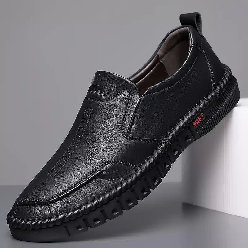 Mocassino nero su base bianca, sfondo grigio.