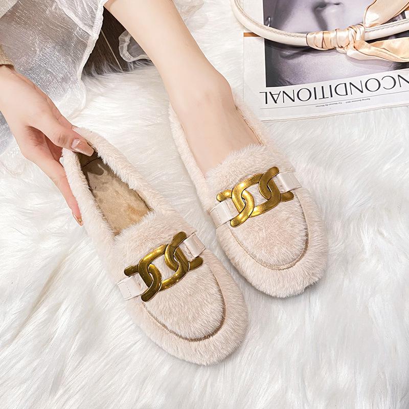 mocassino in pelliccia sintetica con una nappina in cima, indossato da una donna su un tappeto di pile