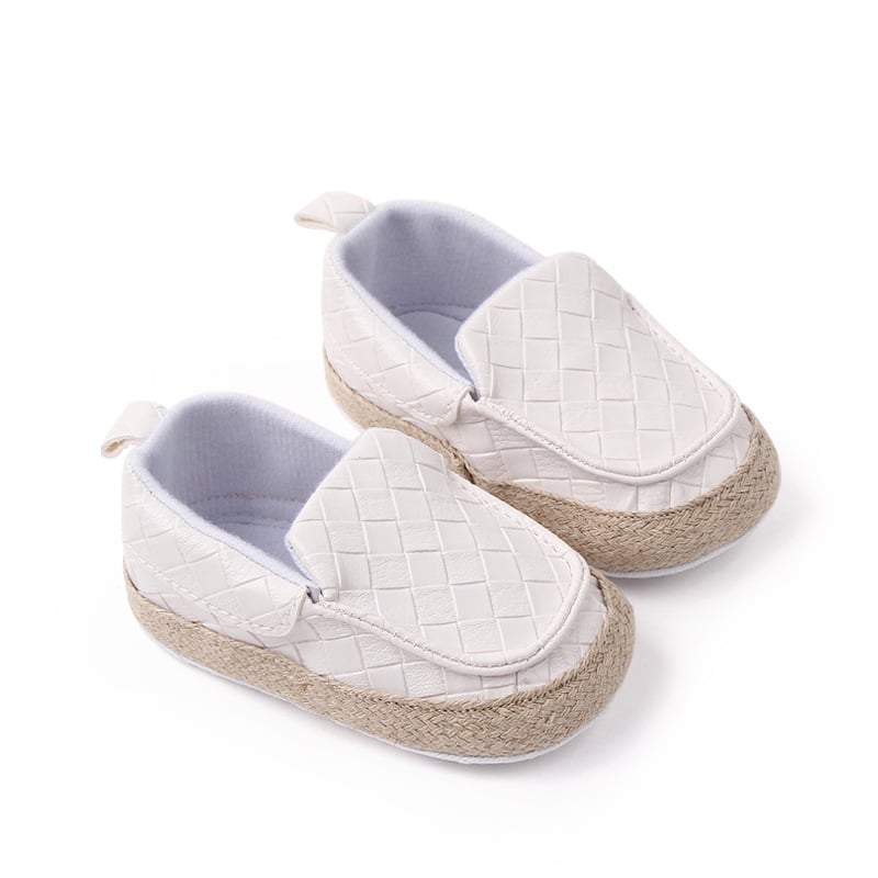 Su uno sfondo bianco, un paio di mocassini marroni a punta quadrata con cinturini in pelle intrecciata sulla parte superiore e corda beige intorno al piede