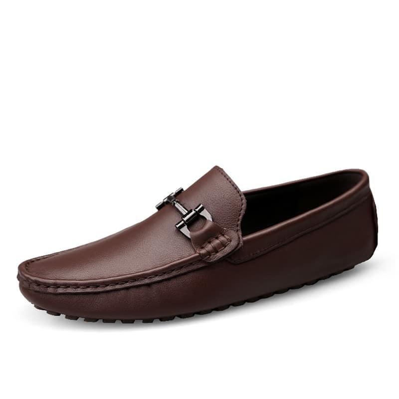 Mocassino in pelle marrone con nappina con morsetto d'oro su sfondo bianco