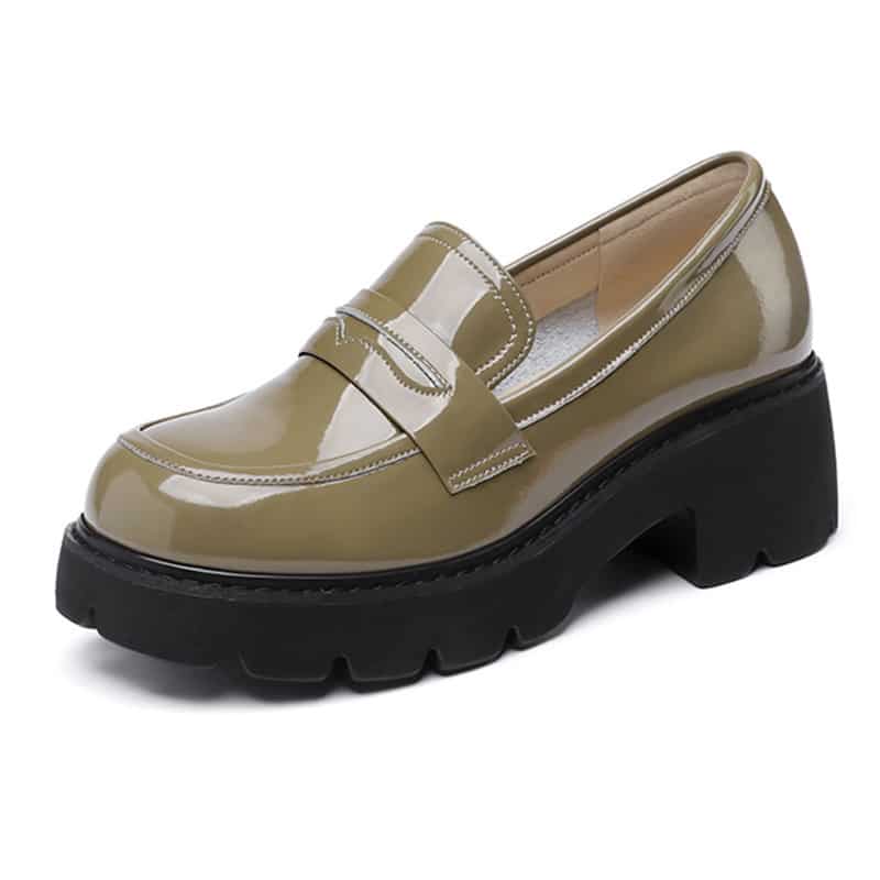 Quattro paia di mocassini in vernice con suole spesse, semplici su un pavimento beige, il paio verde è ai piedi di una donna che indossa jeans azzurri, gli altri paia sono beige, marroni o neri.