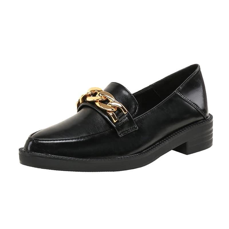 Mocassino in pelle verniciata nera con catena decorativa in oro su sfondo bianco