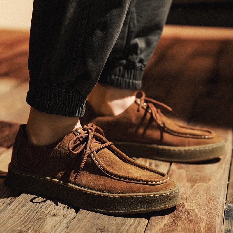 Foto di un mocassino moderno in stile indiano, in pelle scamosciata marrone, indossato da un uomo con jeans