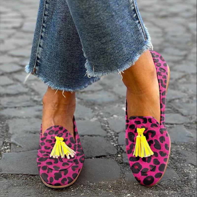 Donna in piedi a gambe incrociate in strada con jeans e mocassini con nappe rosa con stampa leopardata
