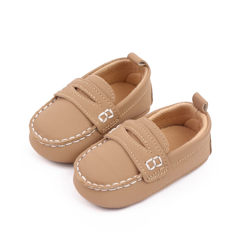 mocassino marrone per bambini in ecopelle con cuciture bianche visibili su sfondo bianco