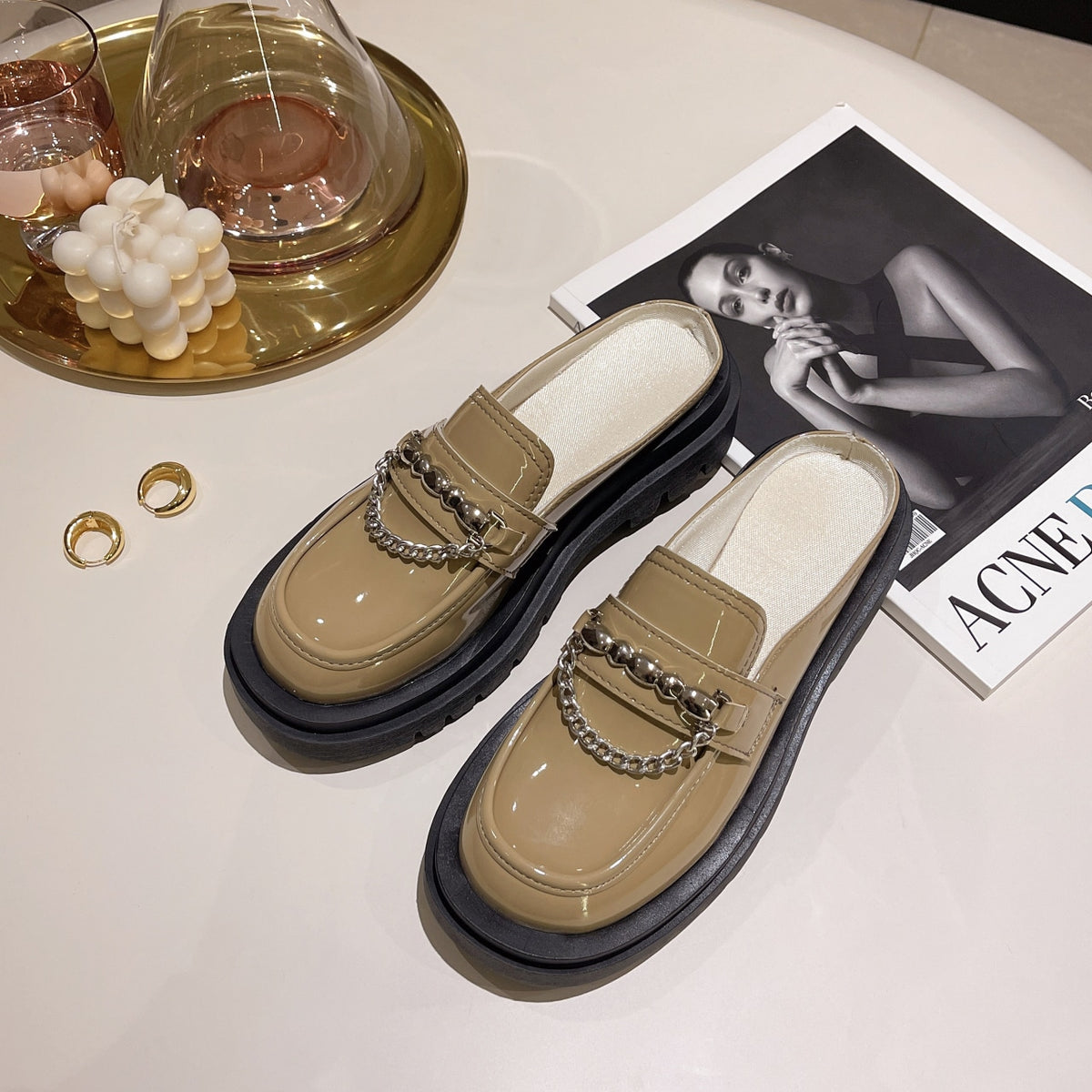 Mocassini beige lucidi su un pavimento con riviste.