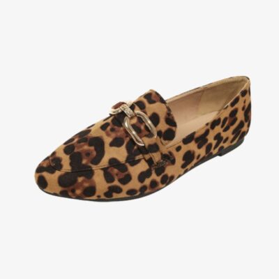Su uno sfondo chiaro, un mocassino di profilo con punta quadrata arrotondata in finto velluto leopardato e fibbie in oro metallizzato sulla tomaia. La suola è piatta e nera.