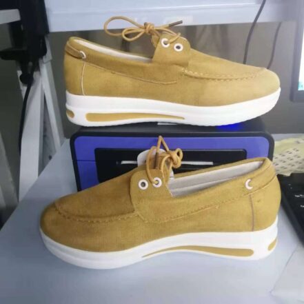 Mocassini gialli con tacco bianco davanti a una scatola.