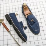Mocassini blu con una scarpa laterale, tutti disposti su una superficie a quadri bianchi.