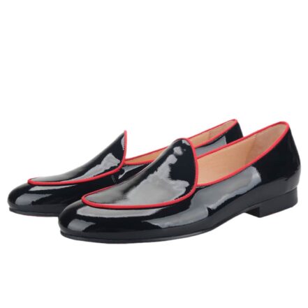 Mocassini neri lucidi con profili rossi sulle dita dei piedi, su sfondo bianco