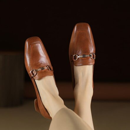 mocassino in pelle marrone con un anello nella parte superiore, indossato da una donna