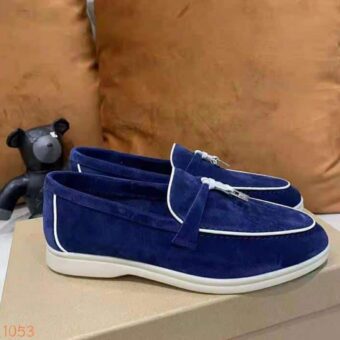 Mocassino in pelle scamosciata blu con profili bianchi e una nappa rigida sulla parte anteriore della scarpa, che si trova su una scatola di scarpe