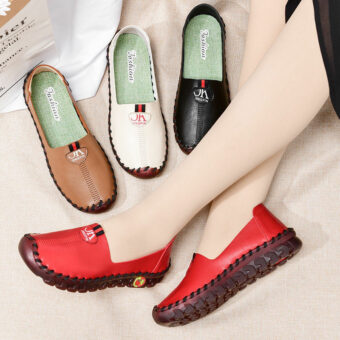 Gambe incrociate con scarpe rosse ai piedi insieme ad altre scarpe marroni, nere e bianche.