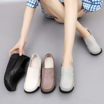 Gamba di una donna con scarpe grigie ai piedi e altre scarpe accanto a lei, nere, bianche e marroni