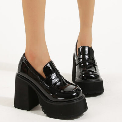 due mocassini da donna in vernice nera lucida con una suola robusta su sfondo bianco
