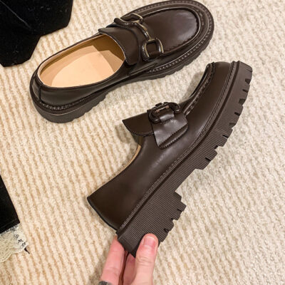 Due mocassini su un pavimento con nappe beige-nero, uno sdraiato