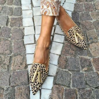 Donna in strada a gambe incrociate che indossa mocassini a punta leopardati dorati
