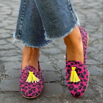 Donna in piedi a gambe incrociate in strada con jeans e mocassini con nappe rosa con stampa leopardata
