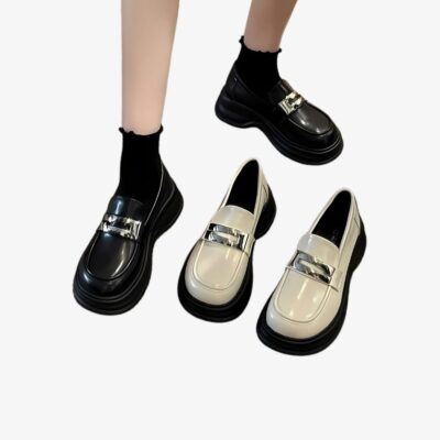 Jambes de femmes portant des mocassins noirs à plateformes, avec une paire de ces mêmes chaussures en couleur beige à côté