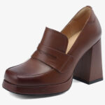 Un mocassino con tacco in pelle da donna di colore marrone su sfondo bianco